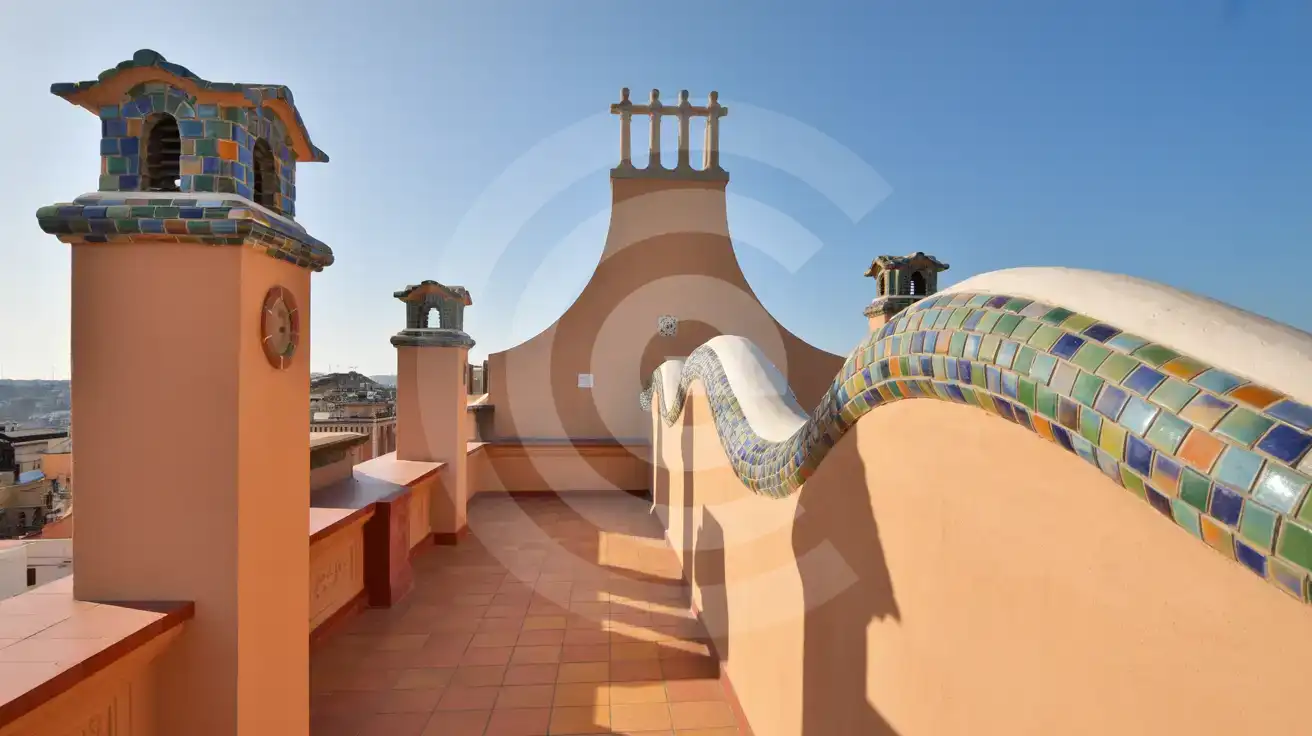 Colorful mosaic chimneys and dragon-spine roof ridge on a modernist building rooftop in Barcelona