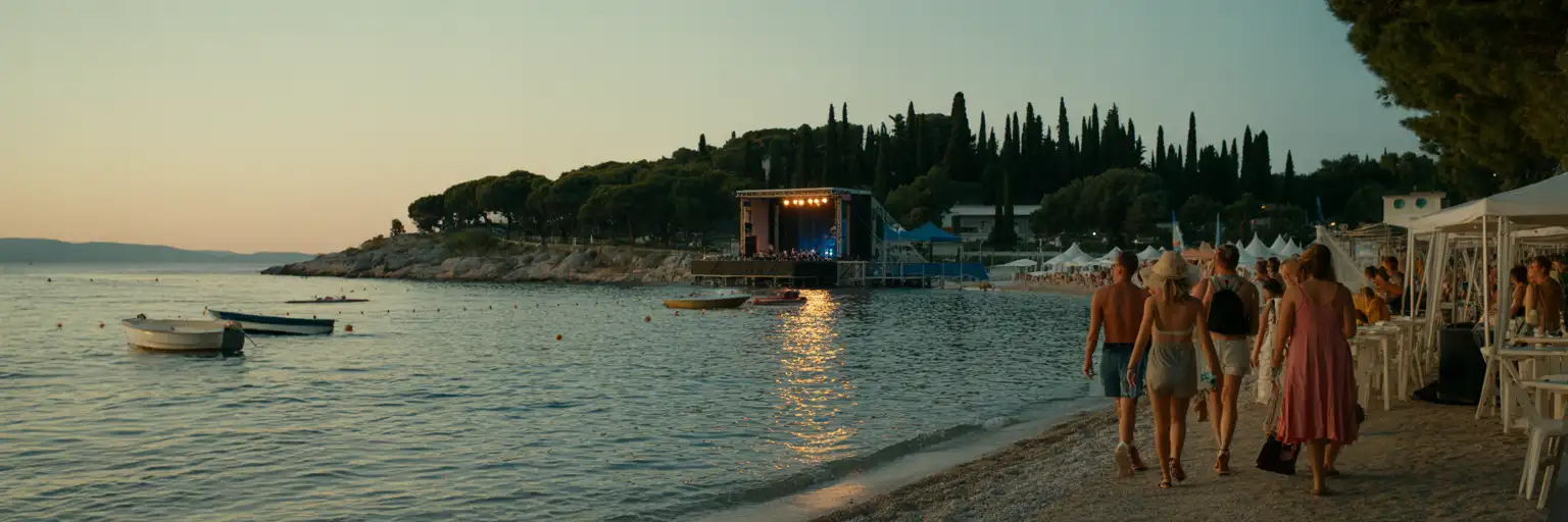Publikum bei einem elektronischen Musikfestival an der Küste in Tisno mit Adriatischem Meer, Booten und Sonnenuntergangsbeleuchtung