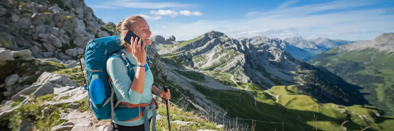 Podróżnik rozmawiający przez telefon na górskim szlaku w Andorze z alpejskimi szczytami w tle