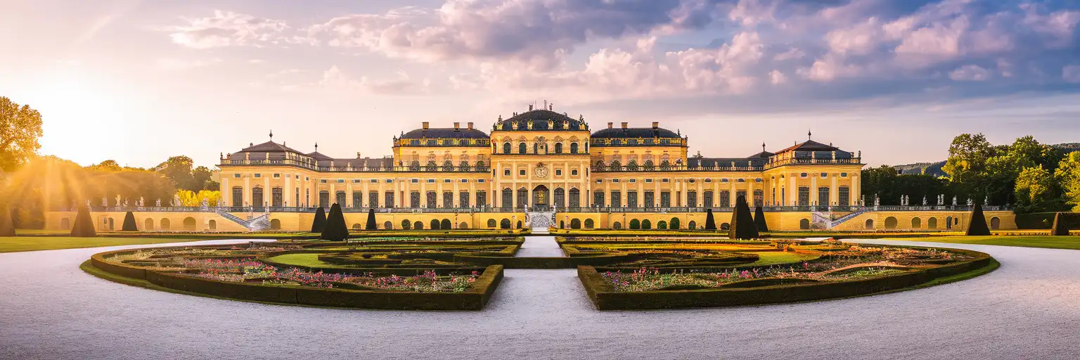 Schönbrunn Palace grand Baroque facade viewed from the Great Parterre gardens at golden hour with the Gloriette on the hilltop behind