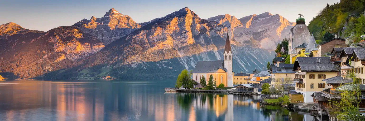 Hallstatt village lakefront with Alpine houses and Dachstein mountains reflected in Hallstätter See at golden hour
