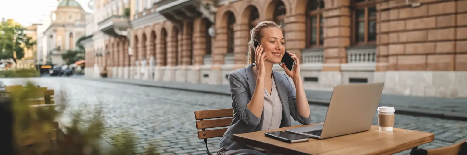Woman making a phone call at a Viennese cafe with laptop and coffee, representing remote work and long-stay travel in Austria