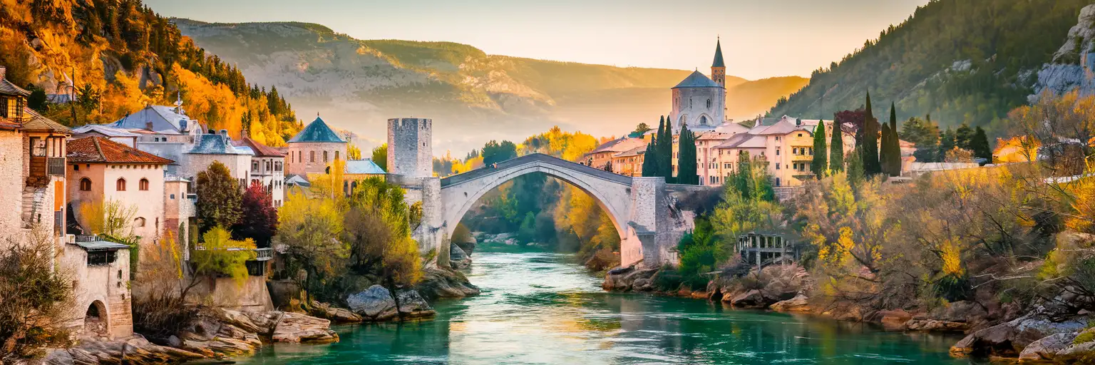 El histórico puente Stari Most sobre el río Neretva de color esmeralda en Mostar, Bosnia y Herzegovina, con casas de piedra de la era otomana en las colinas al atardecer