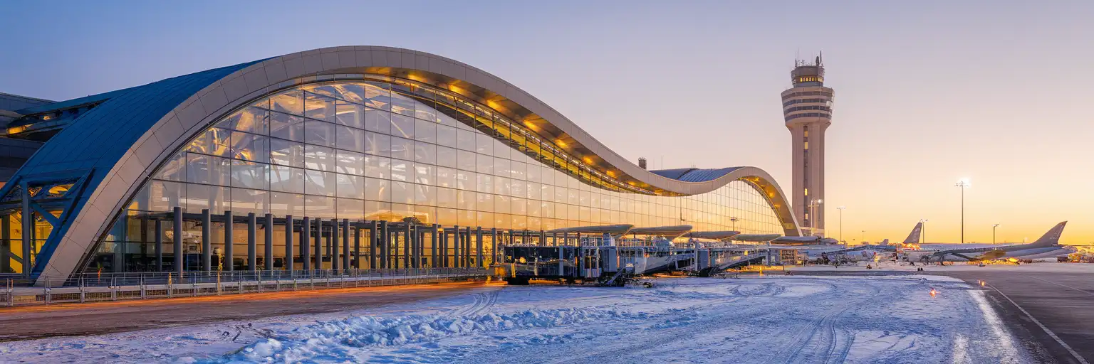 Montréal-Pierre Elliott Trudeau International Airport terminal exterior at golden hour with the YUL control tower and aircraft on the tarmac