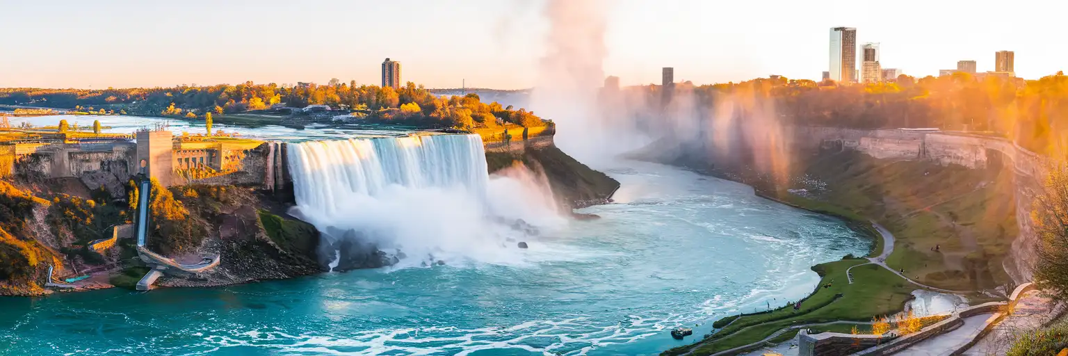 Horseshoe Falls at Niagara Falls Ontario with mist rising into golden hour light and the Canadian observation area along the gorge rim