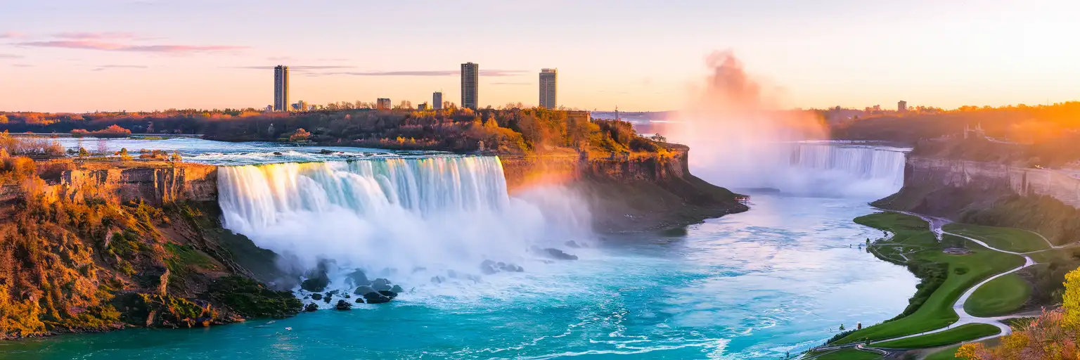 Niagara Falls at golden hour with mist rising and warm sunset light across the Horseshoe Falls
