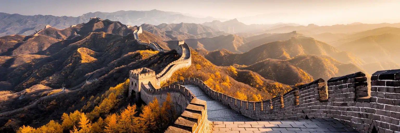 The Great Wall of China winding through mountainous terrain at golden hour with autumn foliage