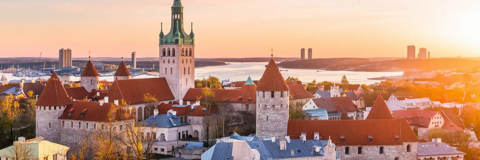 Panoramiczny widok na Stare Miasto w Tallinie z średniowiecznymi wieżami, czerwonymi dachami i iglicą kościoła św. Olafa z widokiem na Morze Bałtyckie o złotej godzinie
