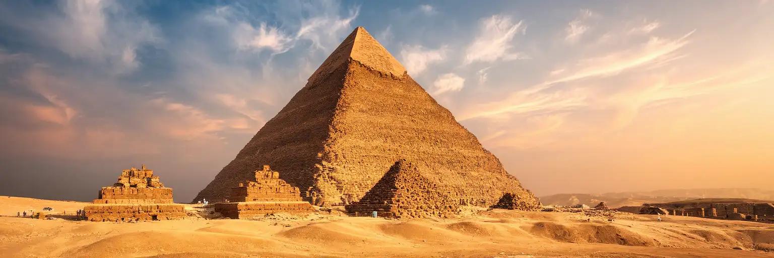 Wide golden-hour exterior view of the Great Pyramid of Giza on the Giza Plateau in Giza Governorate, Cairo, Egypt