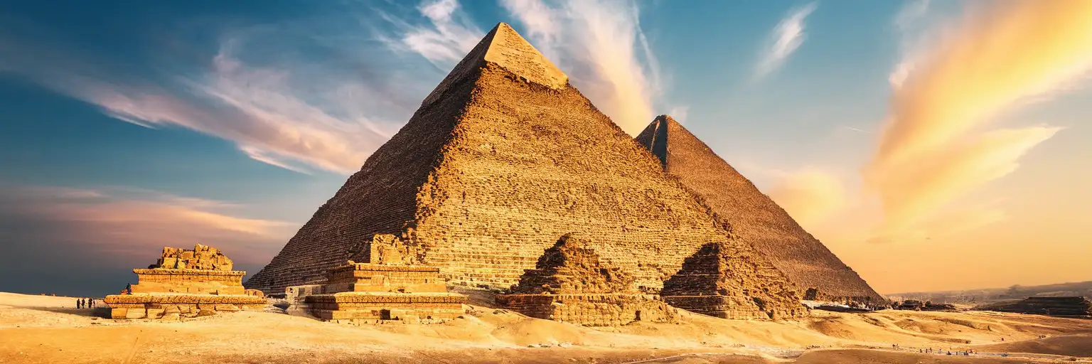 The Great Pyramid of Giza at golden hour with weathered limestone blocks and desert plateau stretching toward the horizon
