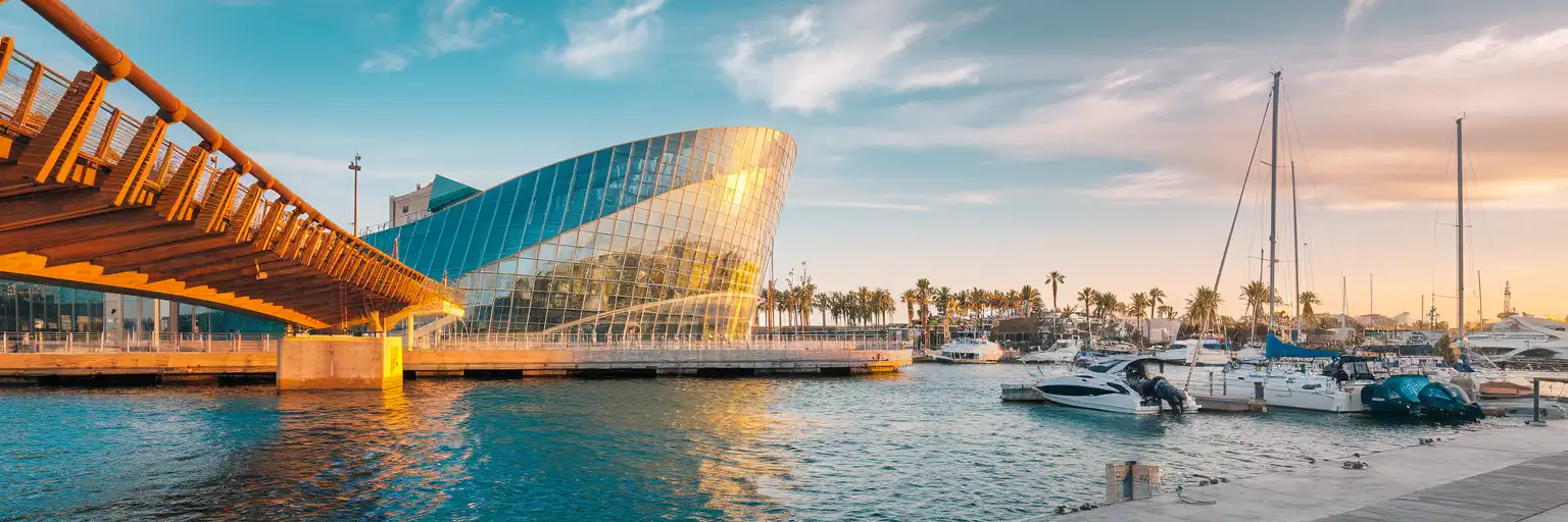 Aquàrium Barcelona curved glass building at Port Vell marina with the Rambla de Mar bridge and Barcelona waterfront at golden hour