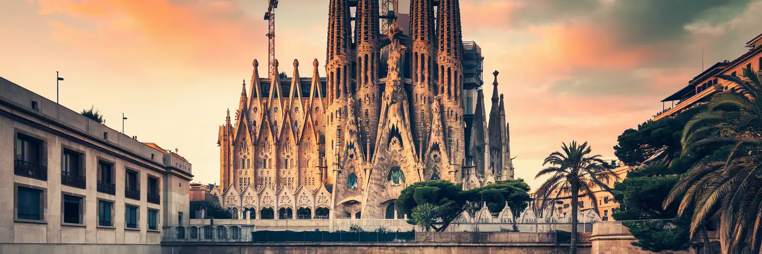 Sagrada Familia basilica spires illuminated at golden hour rising above Barcelona's Eixample district