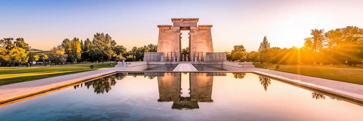 Wide sunset exterior view of Temple of Debod in Madrid with reflecting pools and park surroundings