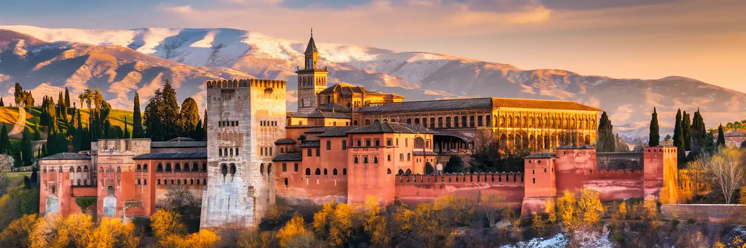 Alhambra palace complex in Granada at golden hour with Sierra Nevada mountains in background