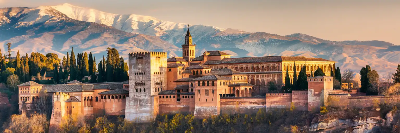 The Alhambra palace complex in Granada at golden hour with Sierra Nevada mountains in the background