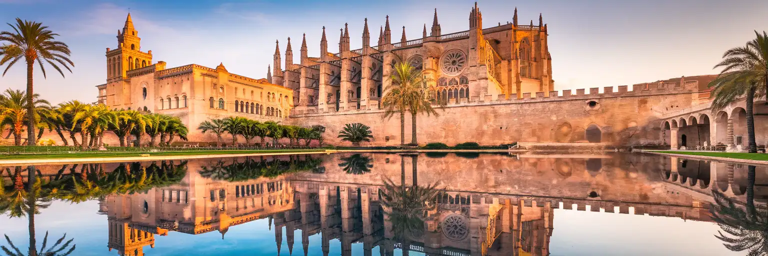 Cathedral of Santa Maria of Palma (La Seu) reflected in Parc de la Mar at golden hour with Mediterranean Sea beyond