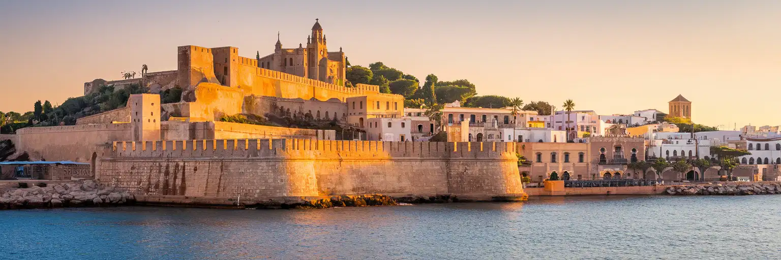 Vista esterna alle luci del tramonto delle mura di Dalt Vila sopra la Città Vecchia di Ibiza e il lungomare a Ibiza, Spagna