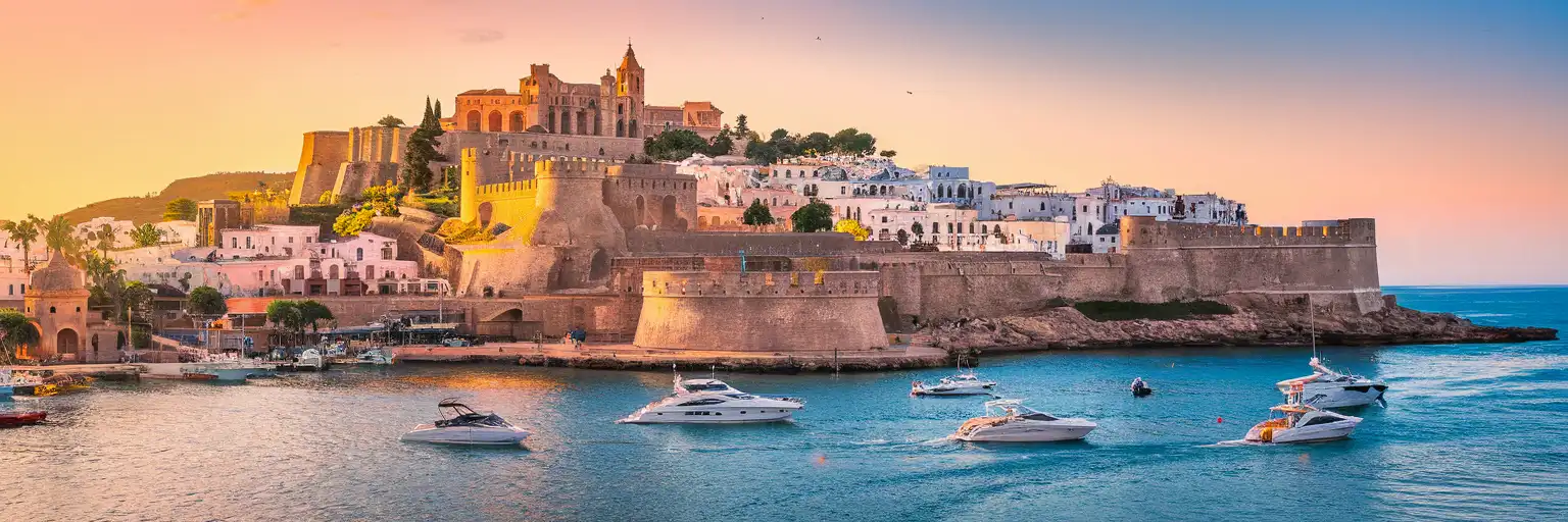 Dalt Vila fortified old town rising above Ibiza harbor at golden hour with Mediterranean waters and whitewashed buildings