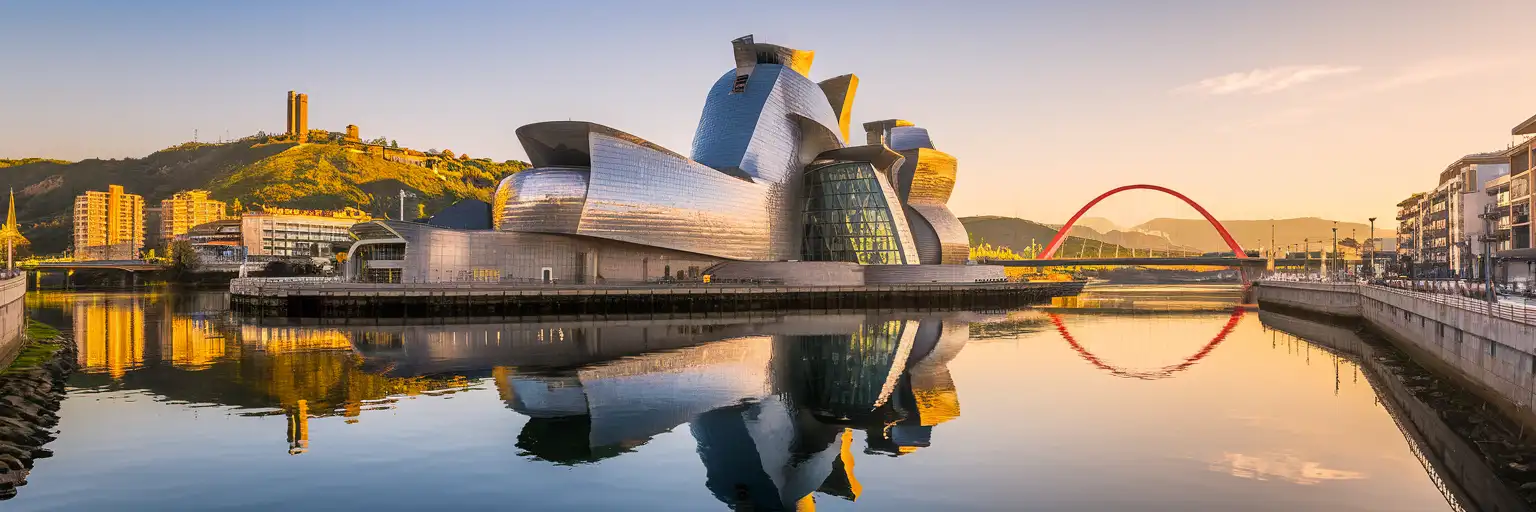 Guggenheim Museum Bilbao with its titanium facade reflected in the Nervión River at golden hour