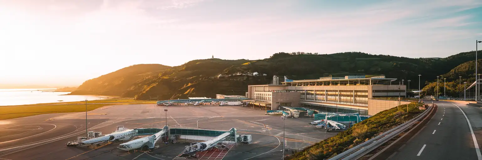 Exterior view of San Sebastián Airport in Hondarribia at golden hour with the terminal and Basque hills beyond