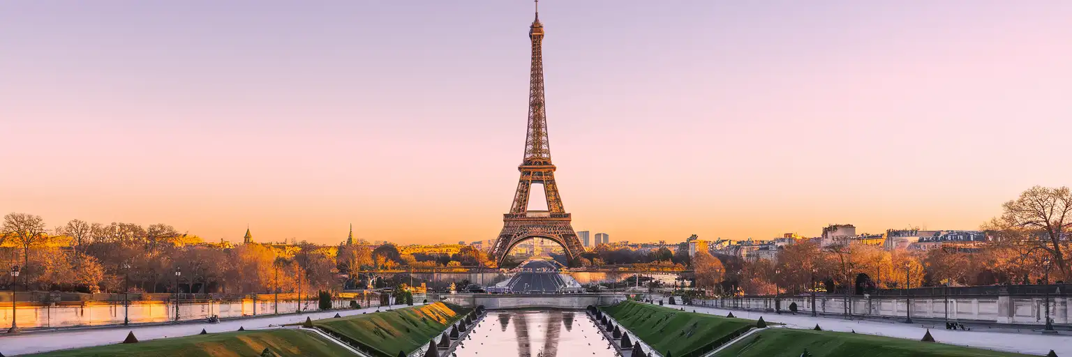 The Eiffel Tower rising from the Champ de Mars at golden hour with the Seine River in the foreground
