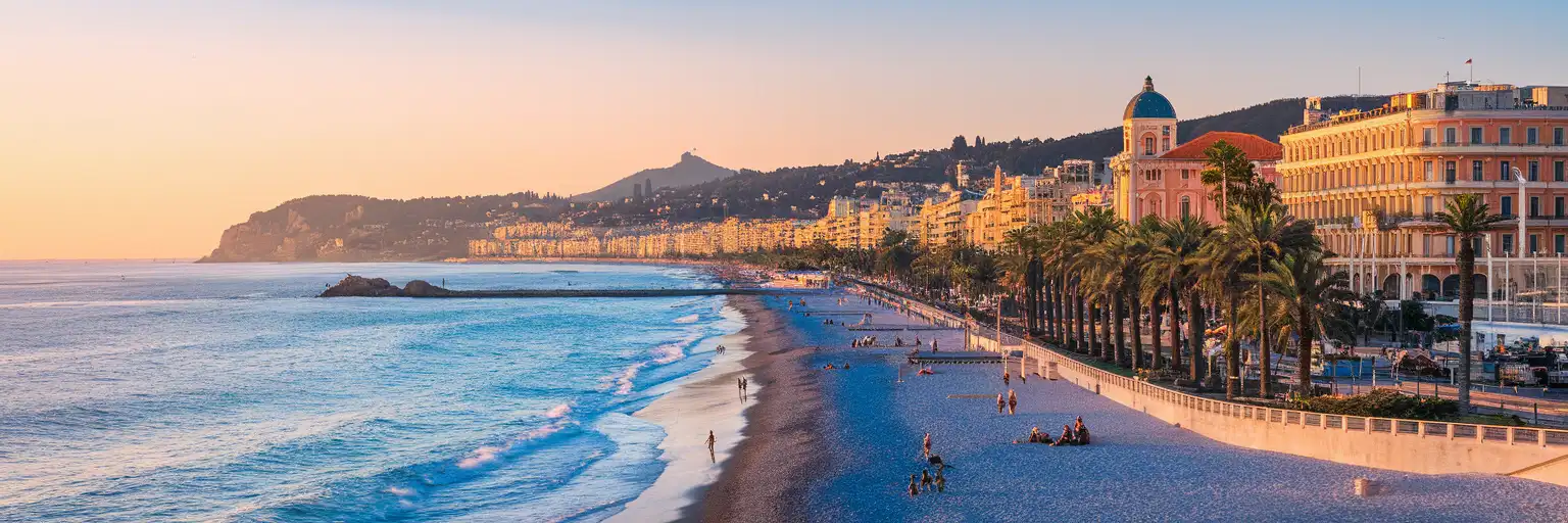 Promenade des Anglais stretching along the Mediterranean coastline in Nice, France at golden hour with palm trees and Belle Époque architecture