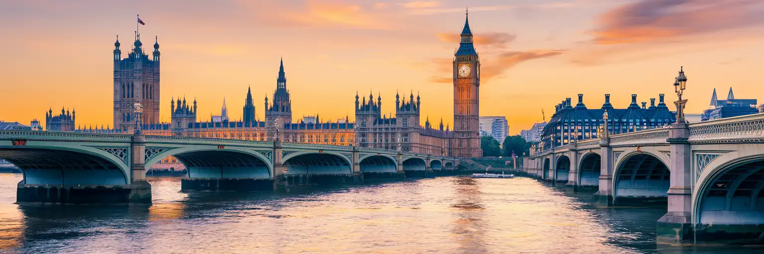 Big Ben and the Houses of Parliament along the River Thames at golden hour with Westminster Bridge in the foreground