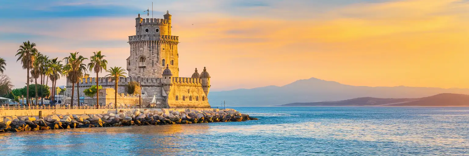 The White Tower of Thessaloniki rising along the Thermaic Gulf waterfront at golden hour with palm trees and distant mountains