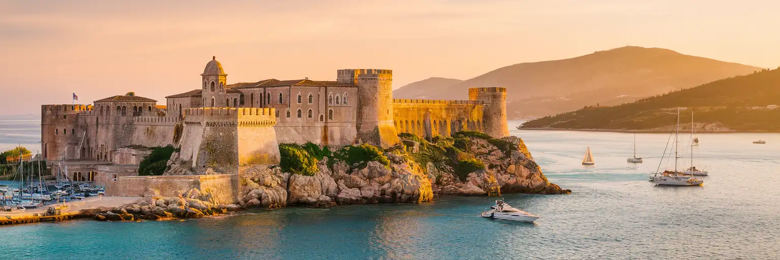 Old Fortress of Corfu rising above the Ionian Sea at golden hour with sailboats in Garitsa Bay