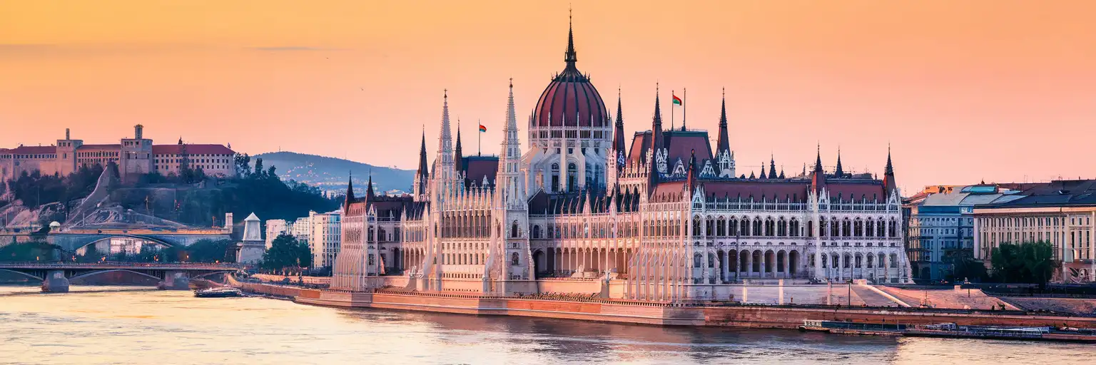 Hungarian Parliament Building along the Danube River in Budapest at golden hour with Chain Bridge visible
