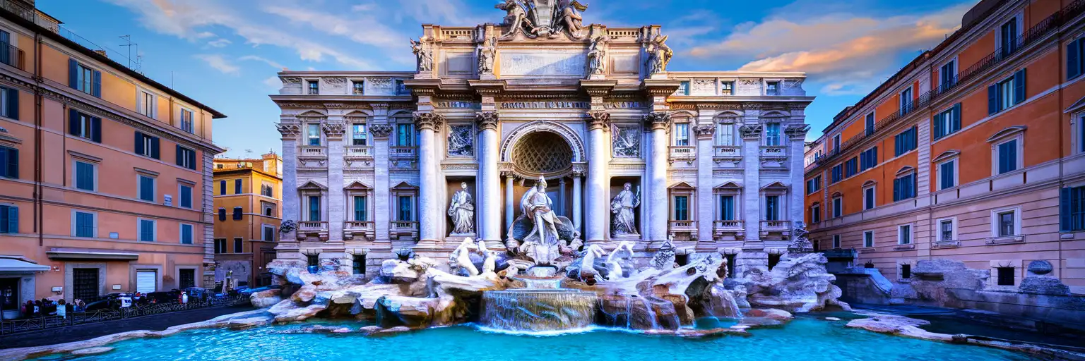 Wide frontal view of Trevi Fountain in Rome at golden hour with Oceanus statue and cascading water