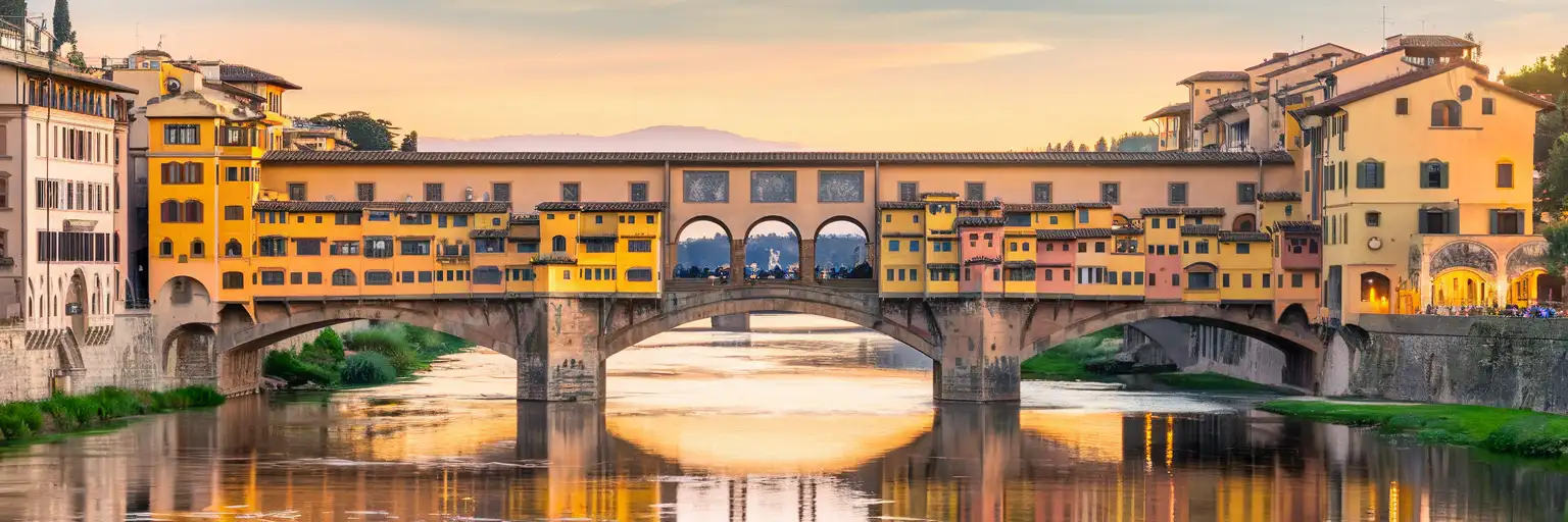 Ponte Vecchio bridge spanning the Arno River in Florence at golden hour with historic jewelry shops lining both sides