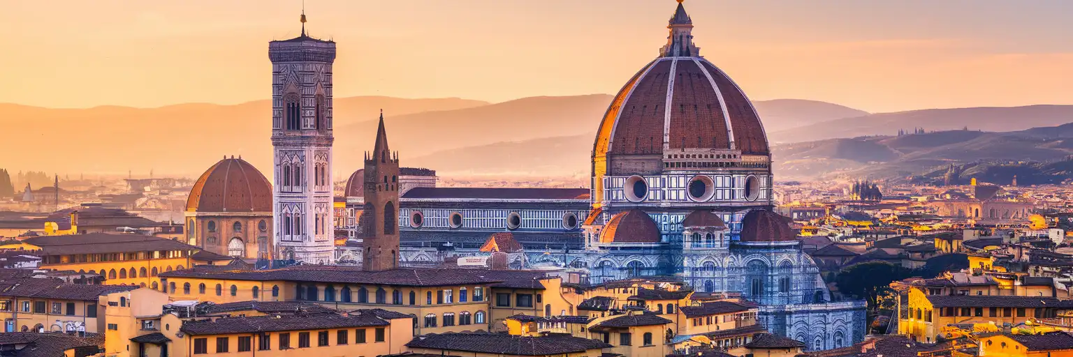 Florence Cathedral and Brunelleschi's Dome rising above red-tiled rooftops at golden hour with Tuscan hills in the background