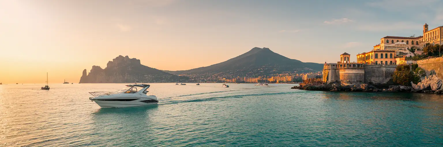 Panoramic view from a tour boat on the Gulf of Naples at golden hour with Mount Vesuvius and Capri island visible