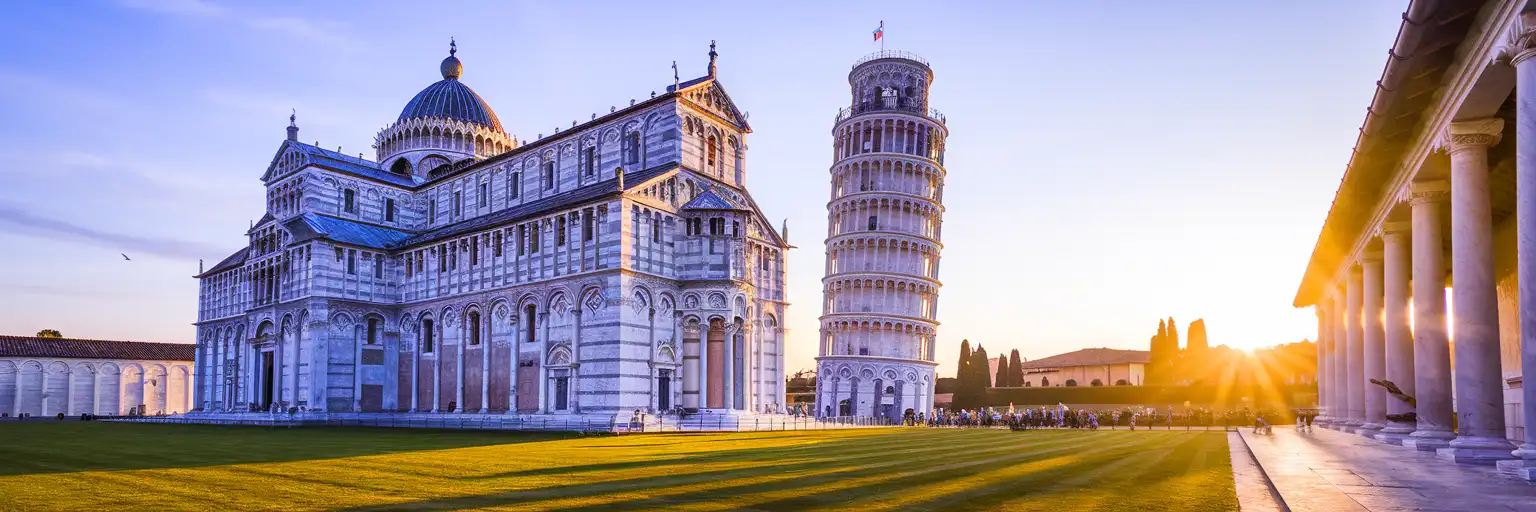 The Leaning Tower of Pisa with its iconic tilt rising above Piazza dei Miracoli at golden hour, white Romanesque marble arcades catching warm sunlight