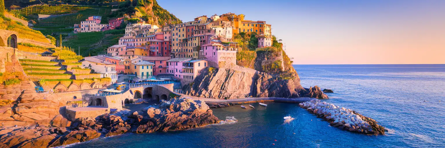 Pastel-colored houses of Manarola village perched on dramatic Cinque Terre cliffs above the Ligurian Sea at golden hour