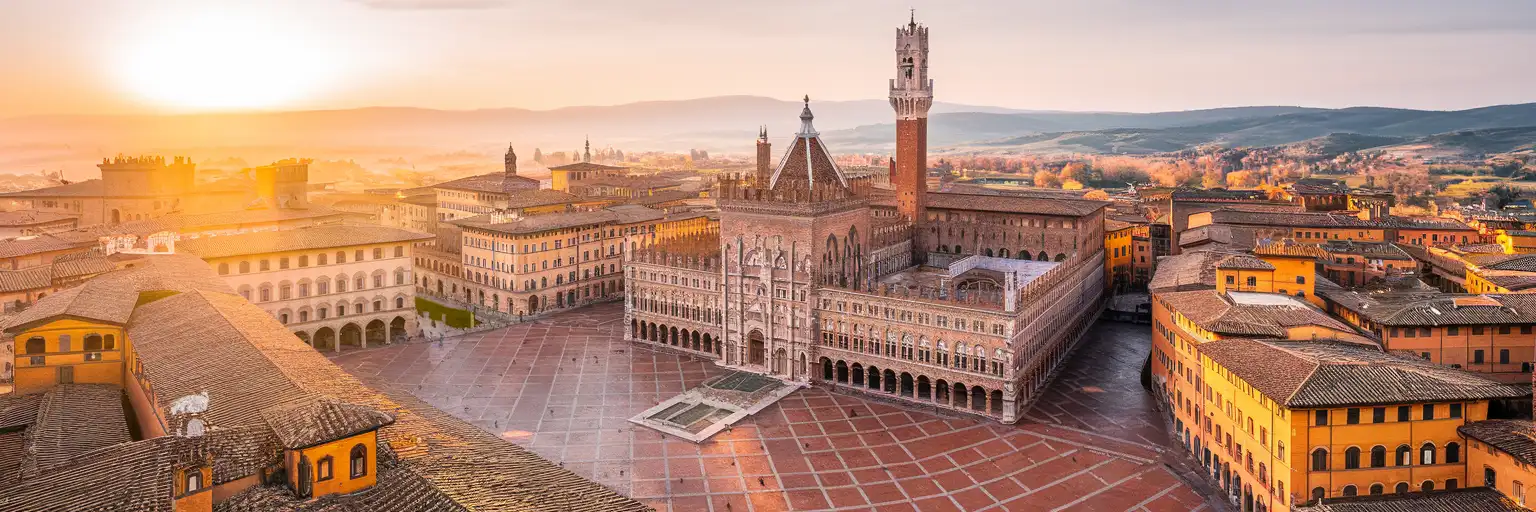 Piazza del Campo and Torre del Mangia in Siena at golden hour with Tuscan hills in the background