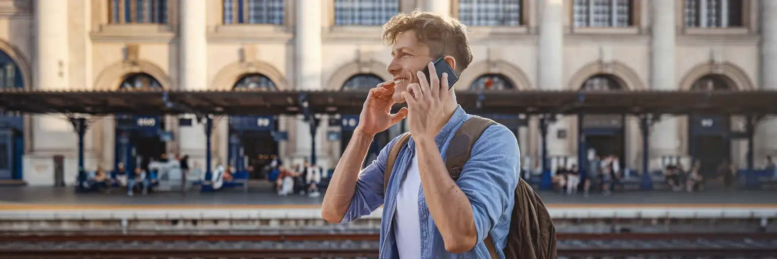 Traveller making a phone call outside an Italian train station in warm afternoon light