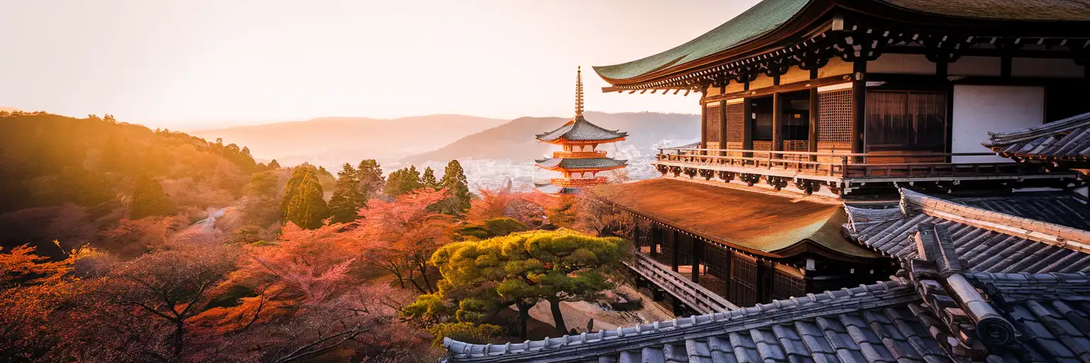 The iconic wooden stage of Kiyomizu-dera main hall extending over the forested Higashiyama hillside at golden hour with the vermilion pagoda visible below