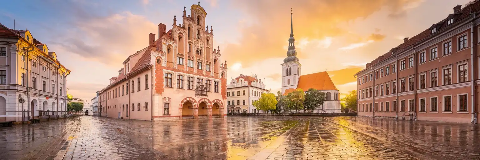 House of the Blackheads and St. Peter's Church spire in Riga Old Town at golden hour with historic facades along the Daugava River