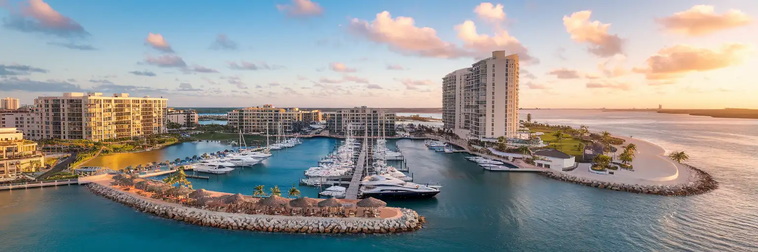Golden-hour exterior view of Puerto Cancún marina and waterfront promenade in Cancún, Mexico