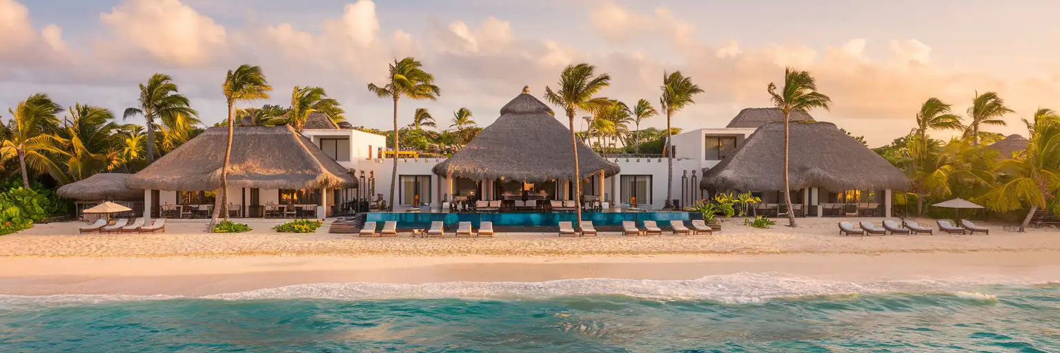 Dreams Tulum Resort & Spa beachfront at golden hour with white buildings, palapa roofs, and turquoise Caribbean waters