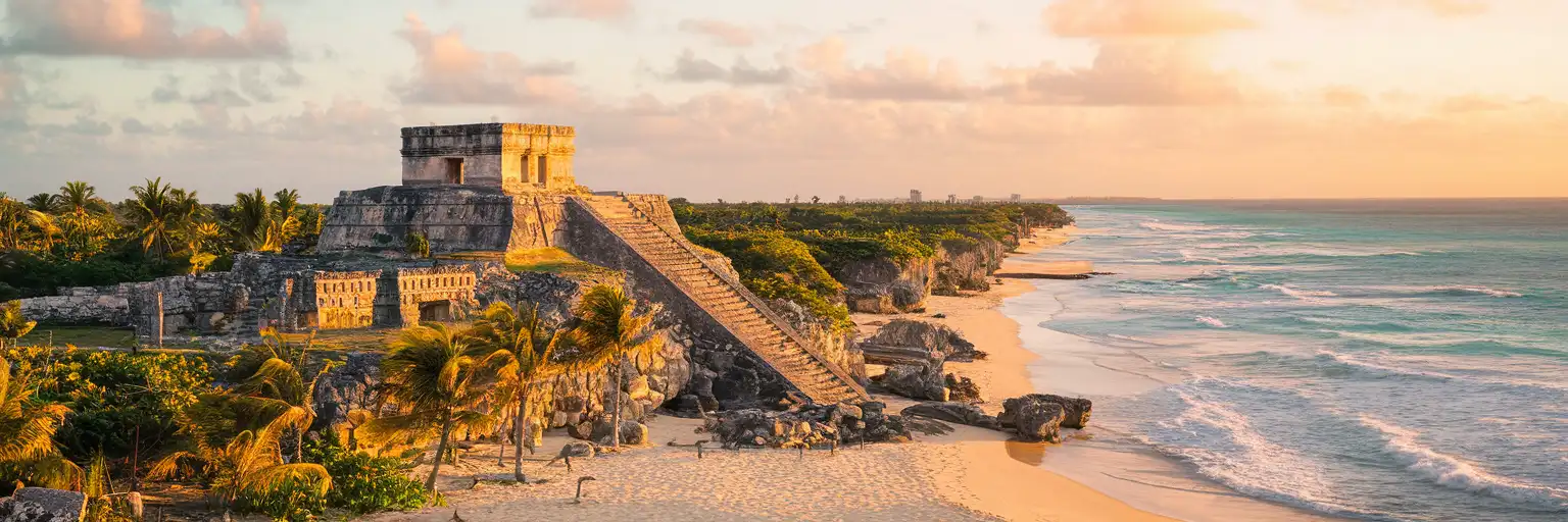 Tulum Archaeological Zone ruins perched on Caribbean clifftops at golden hour with turquoise sea below