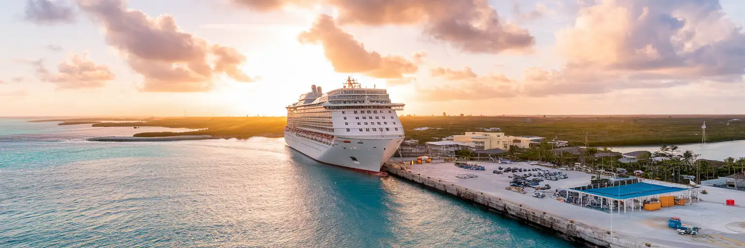 Wide exterior view of Port of Cozumel with cruise pier, docked ship, and turquoise waterfront at sunset