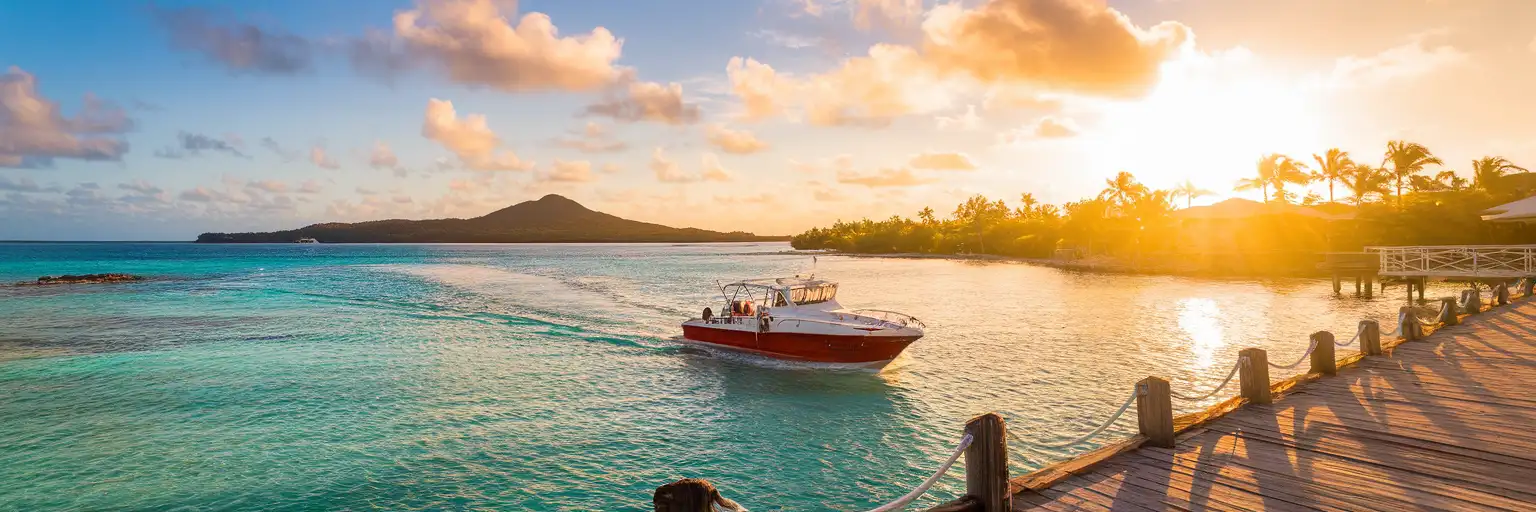 Tour boat departing Cozumel pier toward turquoise Caribbean waters at golden hour