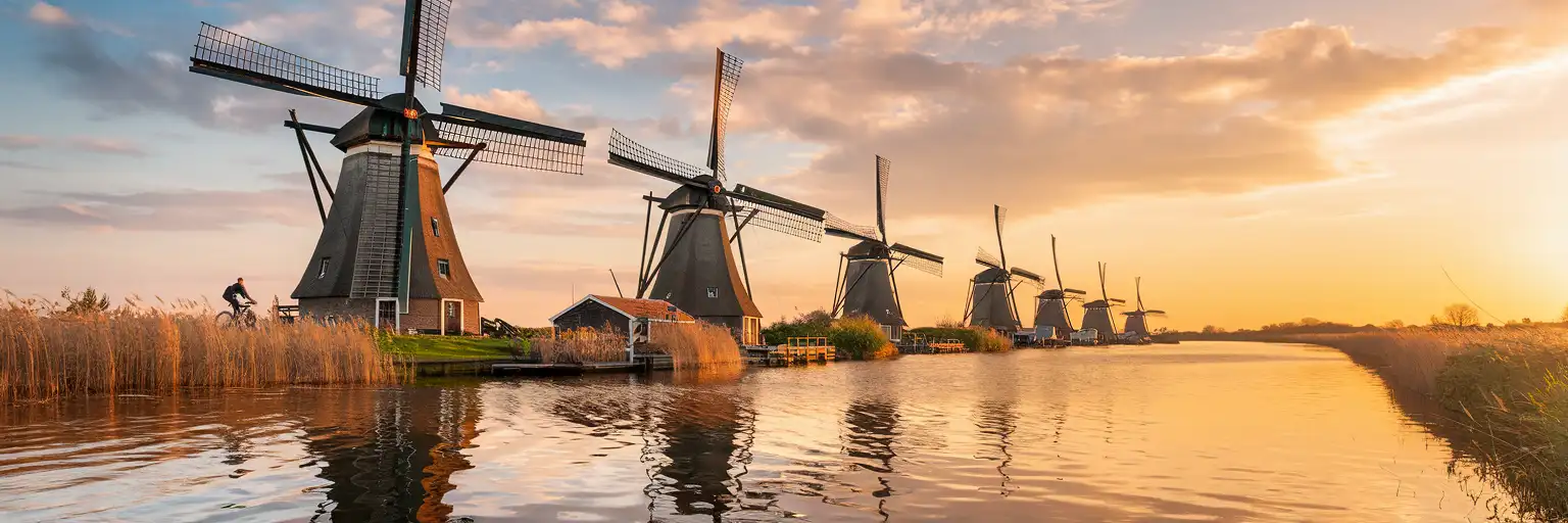 Traditional Dutch windmills at Kinderdijk reflected in a peaceful canal at golden hour in the Netherlands