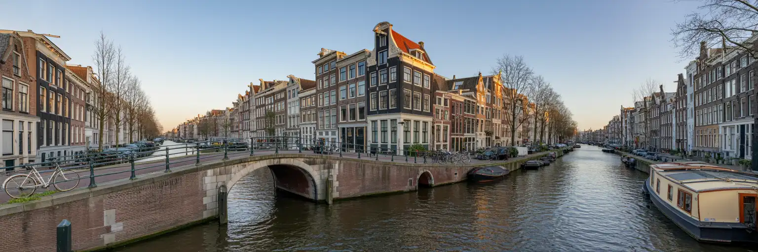 Fachada do Rijksmuseum na hora dourada em Amsterdã com ciclistas na praça Museumplein