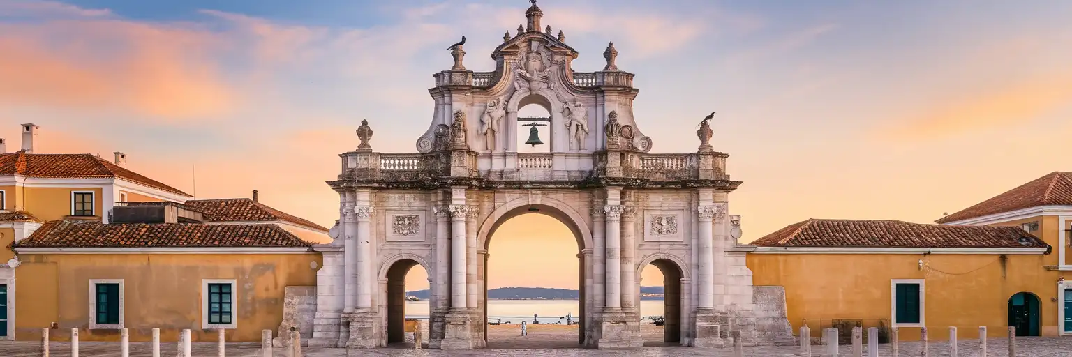 The Arco da Vila gateway in Faro's historic old town at golden hour with stork nests on the bell tower and Ria Formosa lagoon in the distance