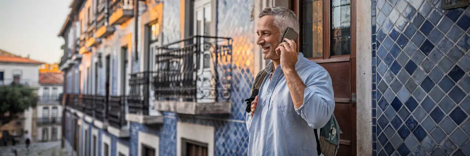 Călător făcând un apel telefonic în fața unei clădiri tradiționale portugheze cu faianță albastră azulejo, în lumina caldă a după-amiezii