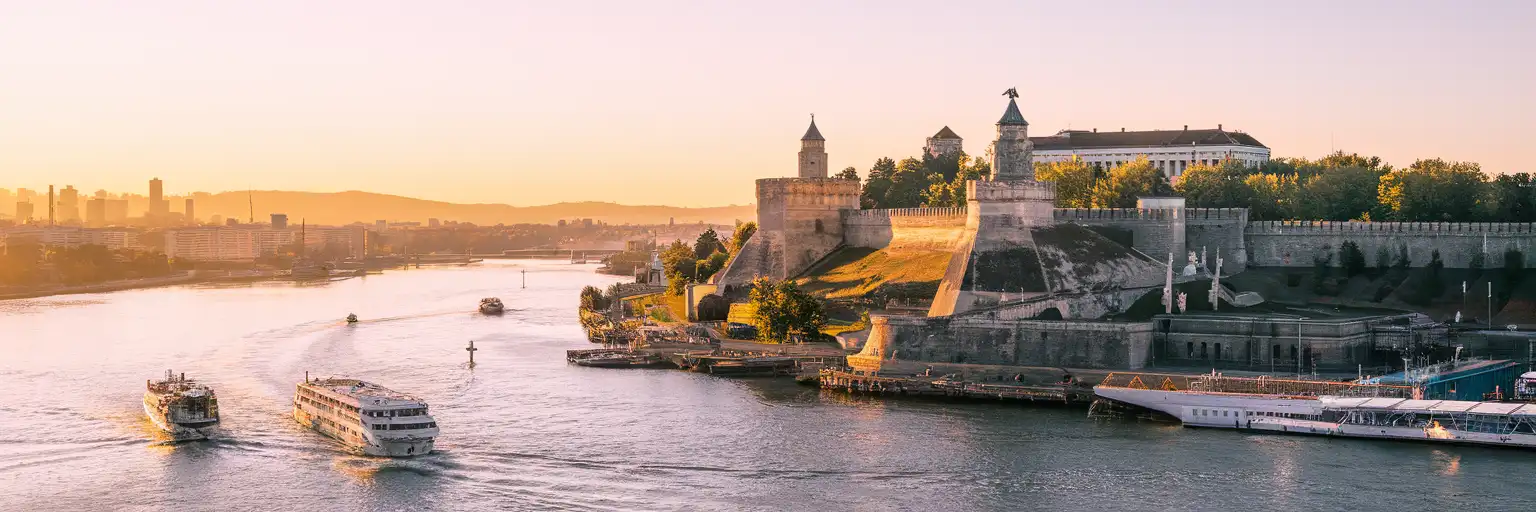 Belgrade Fortress at the confluence of the Sava and Danube rivers during golden hour with the Pobednik monument visible